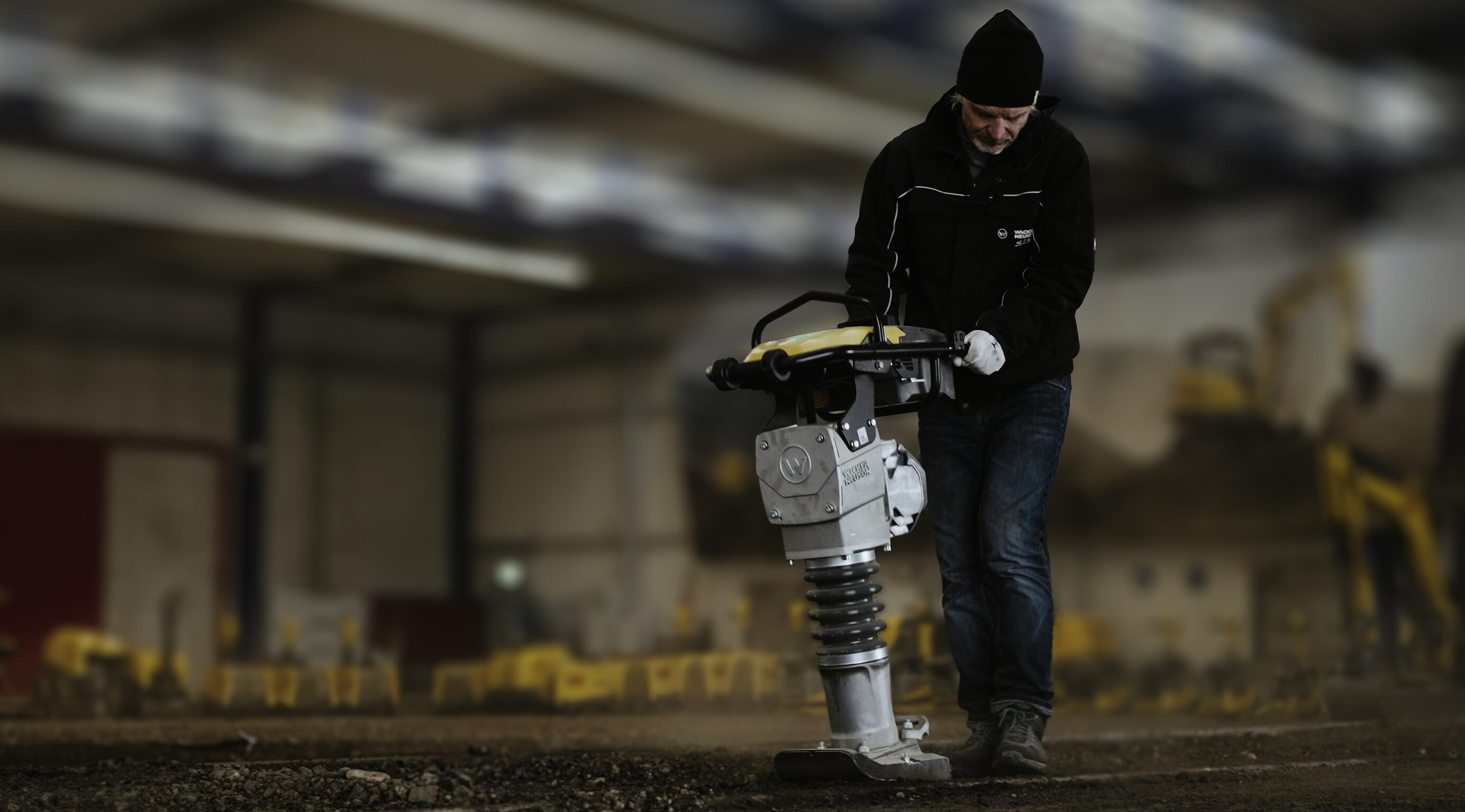 Ouvrier utilisant un pilon pour le compactage du sol dans un centre de formation à la construction en intérieur