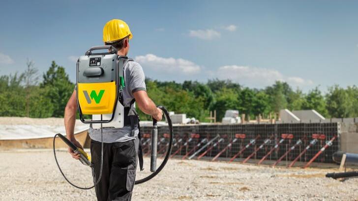 Un ouvrier porte le vibrateur interne haute fréquence sur batterie de Wacker Neuson sur un chantier.
