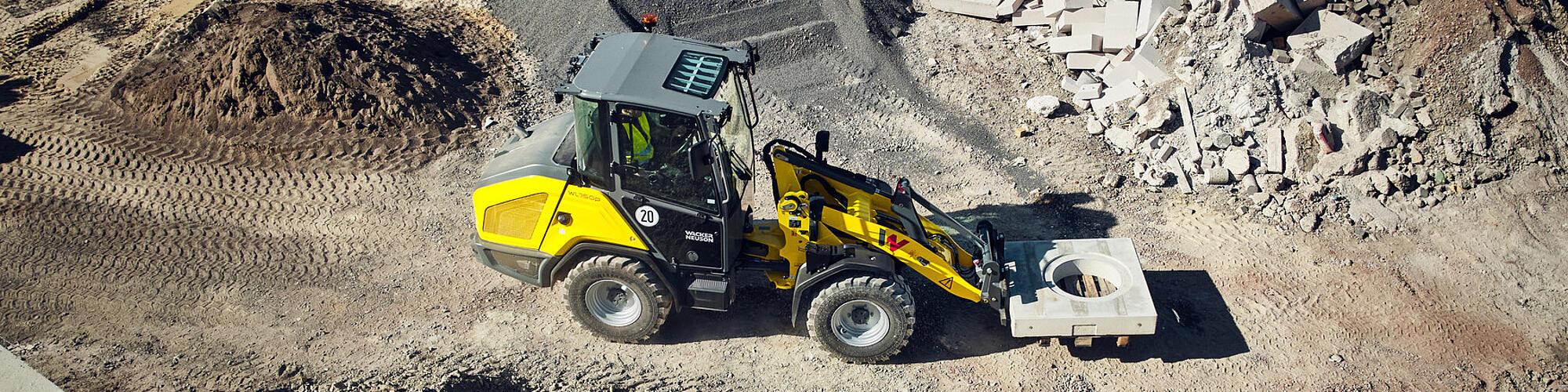 Chargeuse sur pneus haute performance Wacker Neuson WL750p transportant un élément en béton sur un chantier.