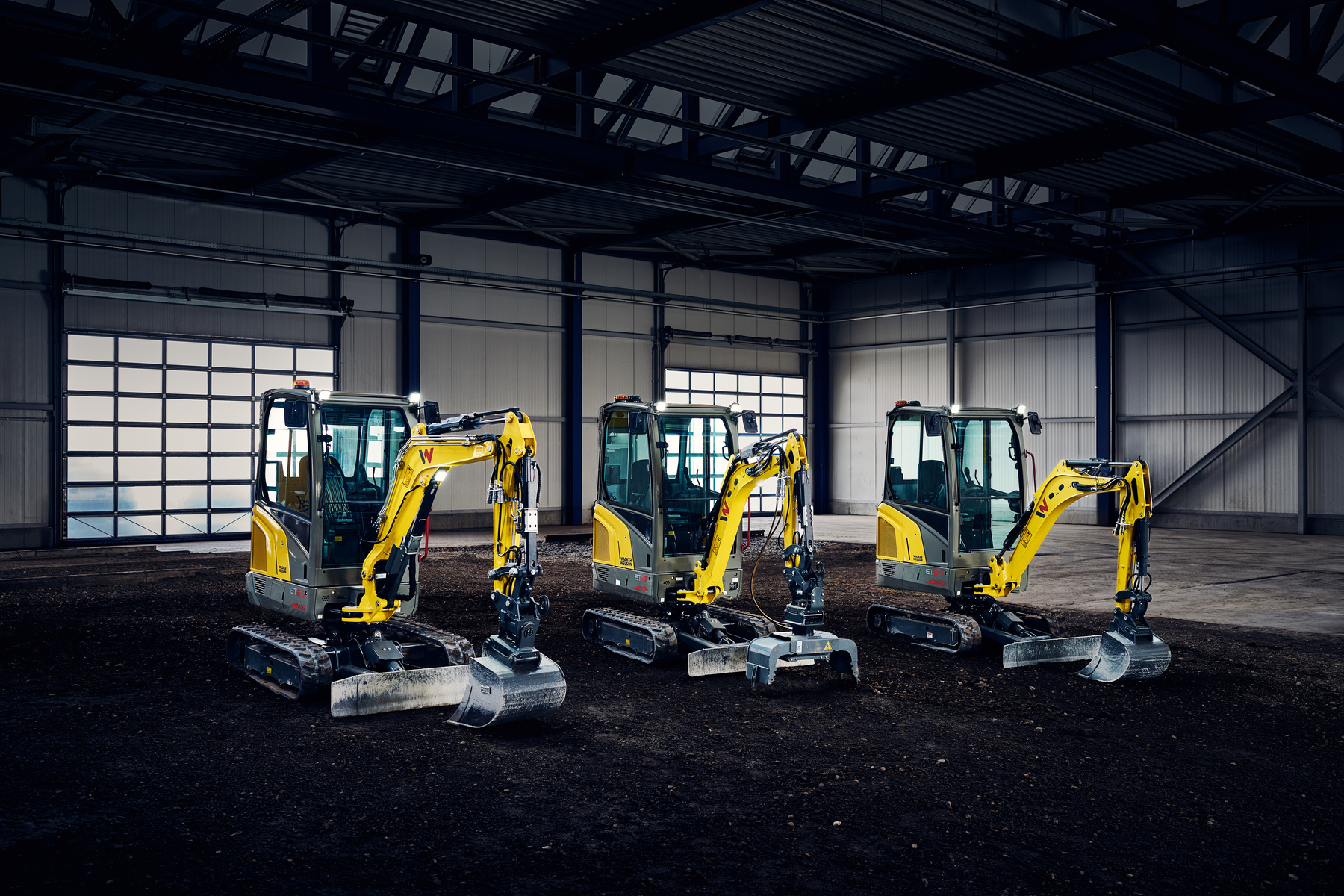 Des mini-pelles sont garées dans le hangar industriel